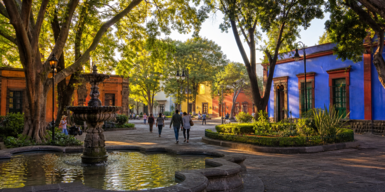 Plaza arbolada de Coyoacán con fuente y arquitectura histórica al amanecer